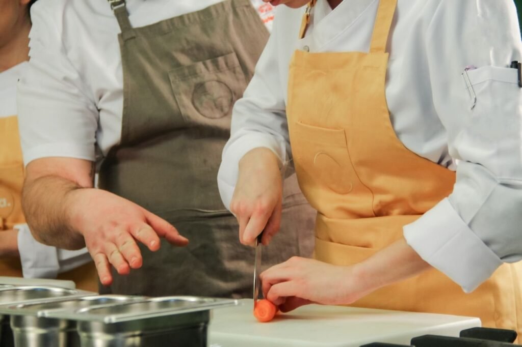 Close-up of chefs chopping carrots in a modern kitchen setting.